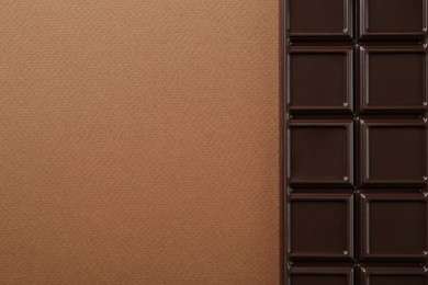 Photo of Tasty chocolate bar on brown background, top view. Space for text