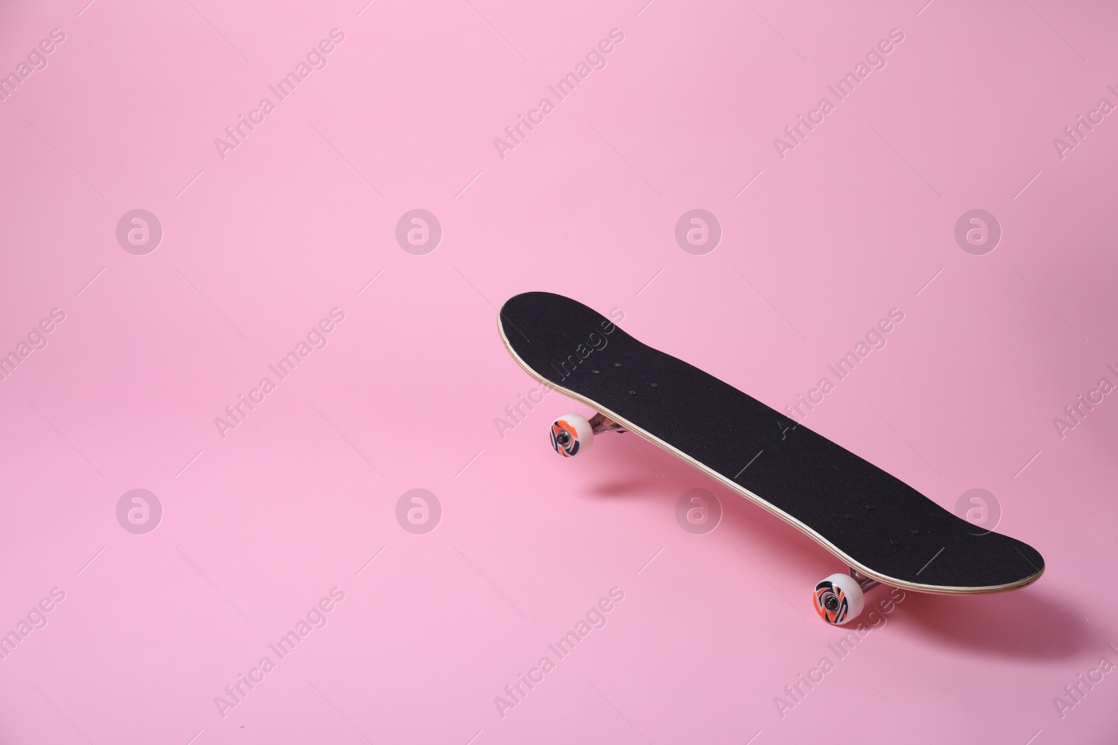 Photo of One skateboard on pink background, space for text. Sports equipment