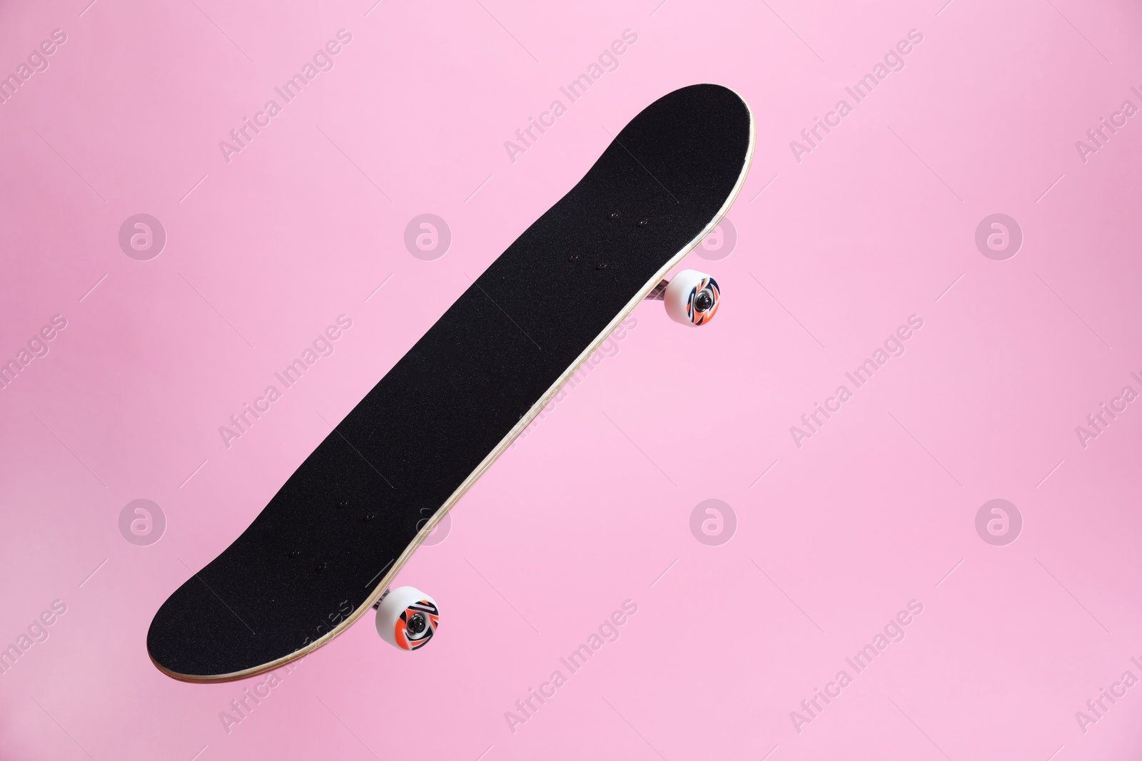 Photo of One skateboard on pink background, space for text. Sports equipment