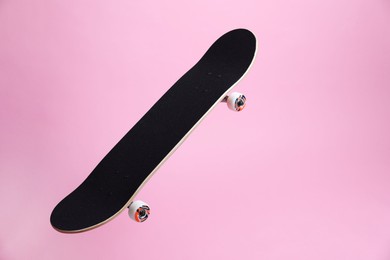 Photo of One skateboard on pink background, space for text. Sports equipment