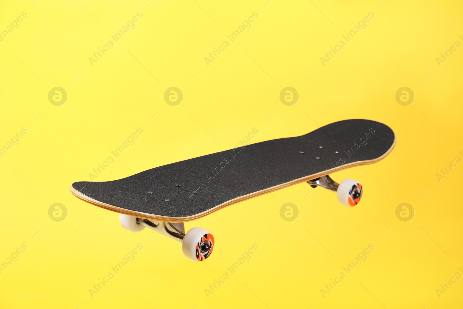 Photo of One skateboard on yellow background. Sports equipment