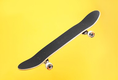 Photo of One skateboard on yellow background. Sports equipment