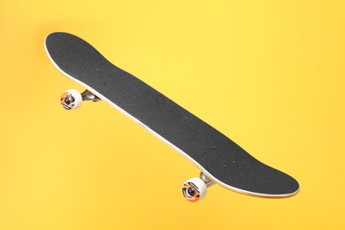 Photo of One skateboard on yellow background. Sports equipment