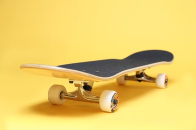 Photo of One skateboard on yellow background, closeup. Sports equipment