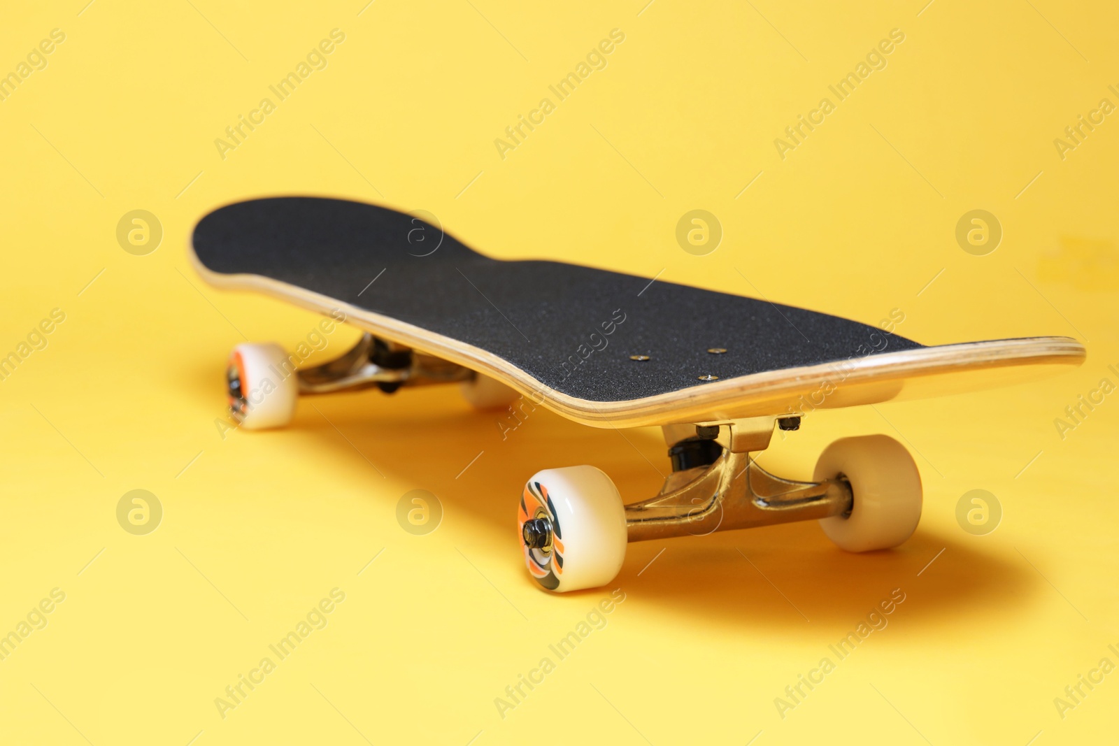 Photo of One skateboard on yellow background, closeup. Sports equipment