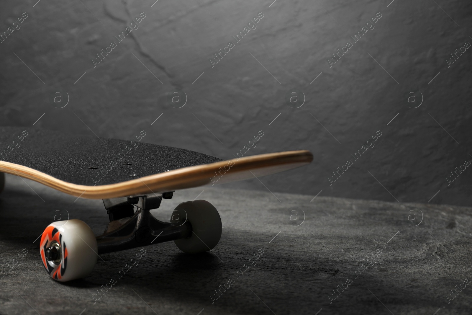 Photo of One modern skateboard on grey surface, closeup. Space for text