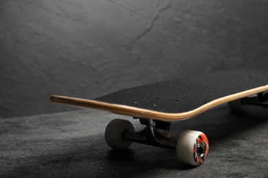 Photo of One modern skateboard on grey surface, closeup. Space for text