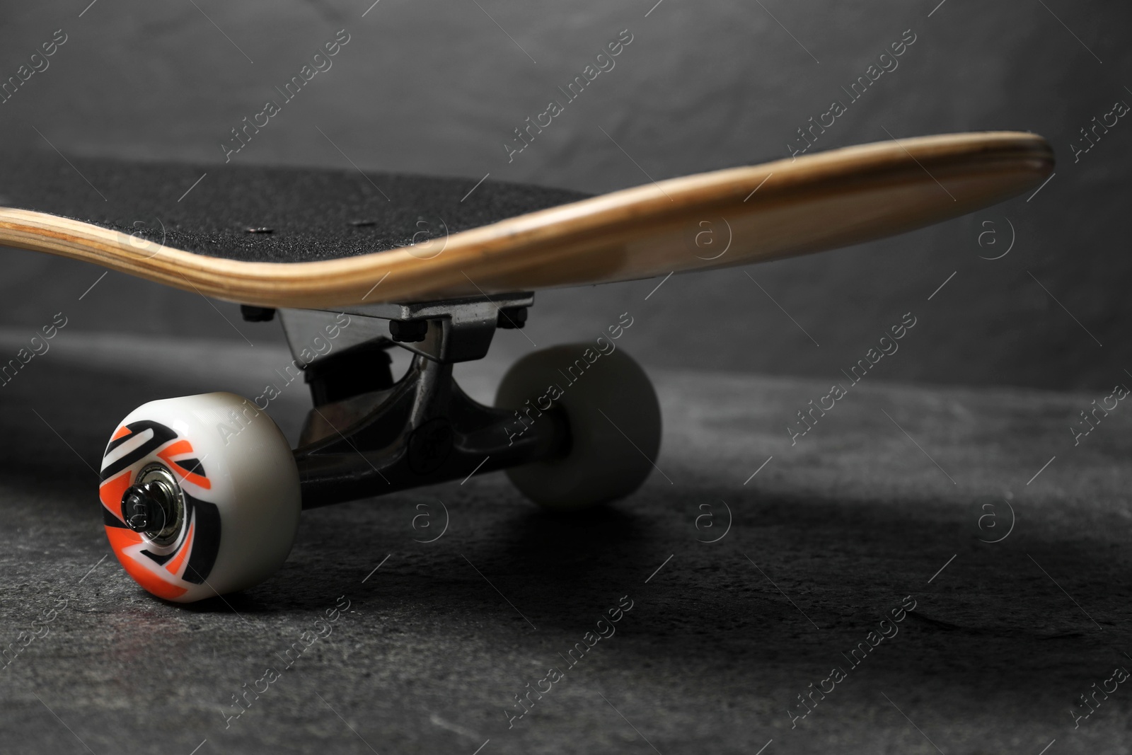 Photo of One modern skateboard on grey surface, closeup