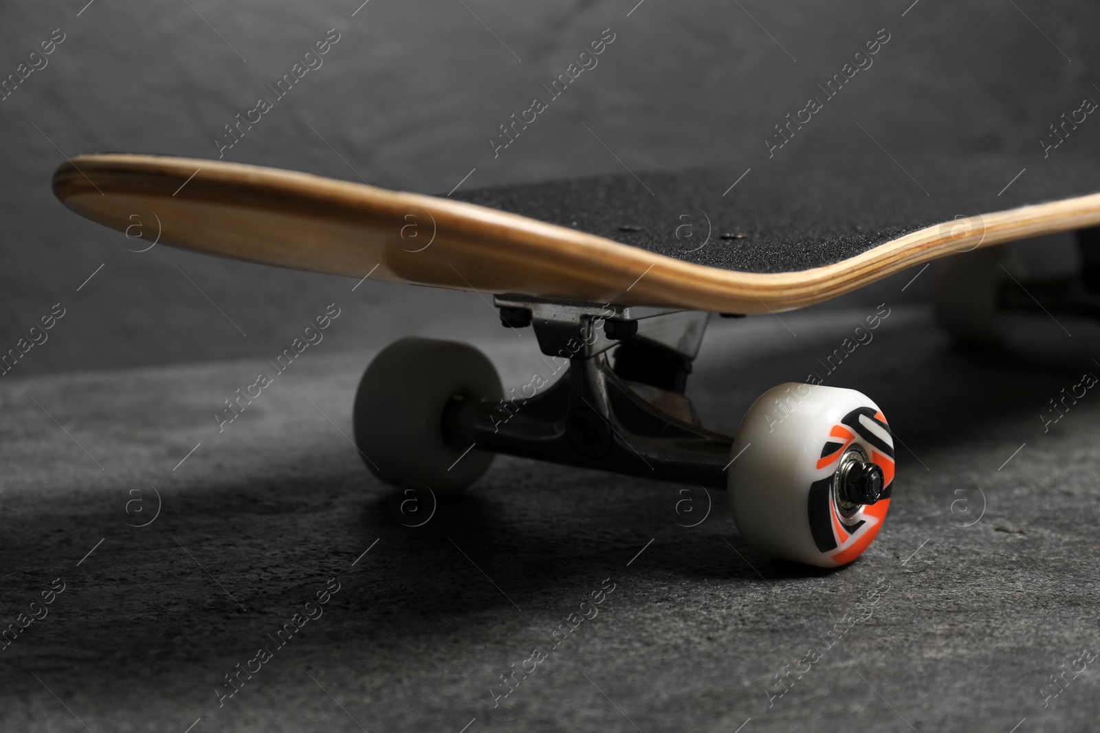 Photo of One modern skateboard on grey surface, closeup