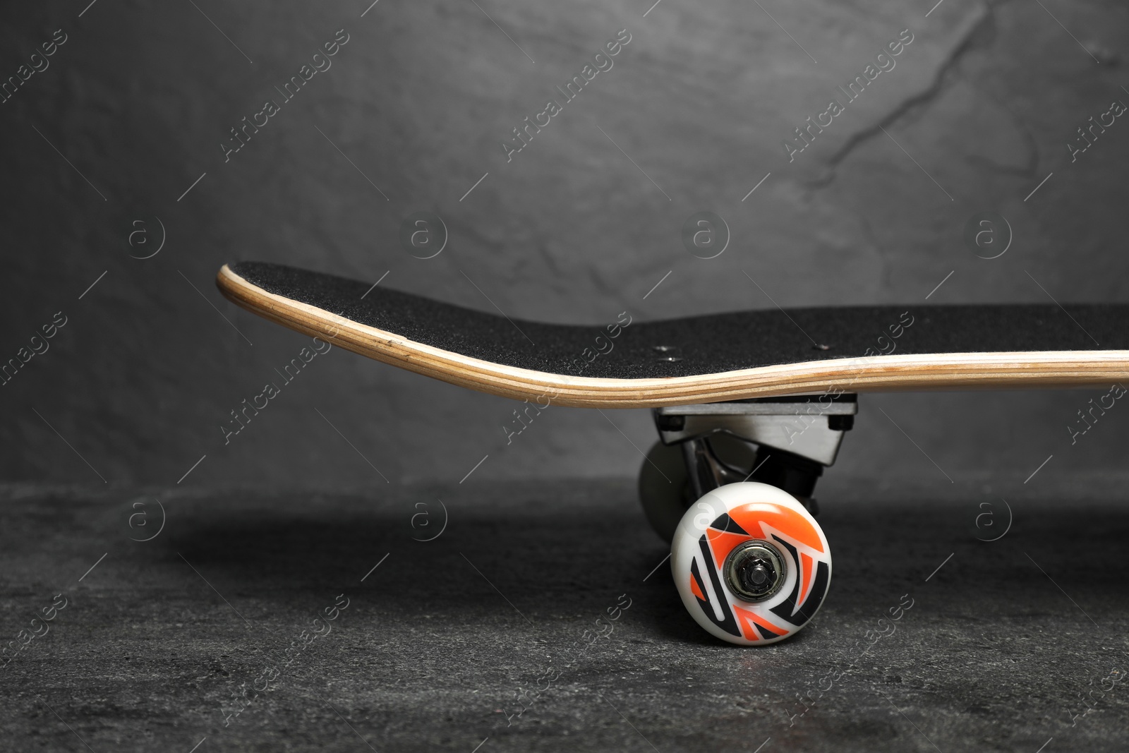 Photo of One modern skateboard on black surface, closeup