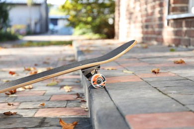 Photo of One modern skateboard on paved pathway outdoors, closeup