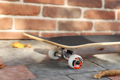 Photo of One skateboard on paved pathway near brick wall outdoors, closeup