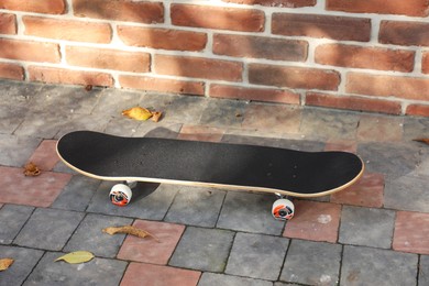 Photo of One skateboard on paved pathway near brick wall outdoors