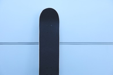 Photo of One modern skateboard near light wall outdoors