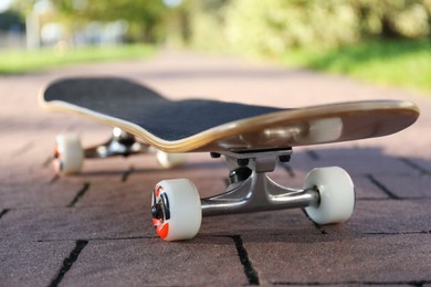 Photo of One modern skateboard on paved pathway outdoors, closeup