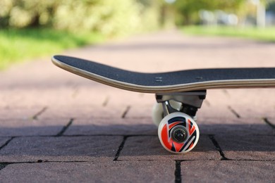 Photo of One modern skateboard on paved pathway outdoors, closeup