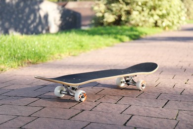 Photo of One modern skateboard on paved pathway outdoors