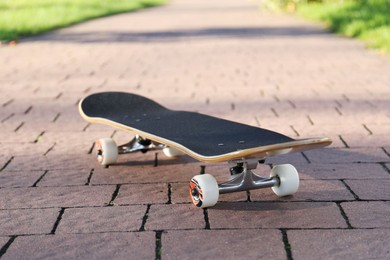 Photo of One modern skateboard on paved pathway outdoors, closeup