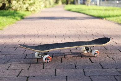 Photo of One modern skateboard on paved pathway outdoors