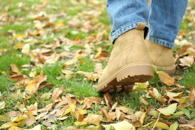 Photo of Man walking on green grass with fallen leaves, closeup. Space for text