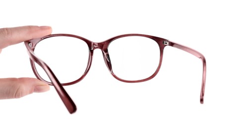 Photo of Woman holding glasses with brown frame on white background, closeup