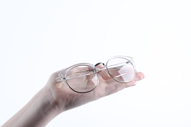 Woman holding glasses with stylish transparent frame on white background, closeup