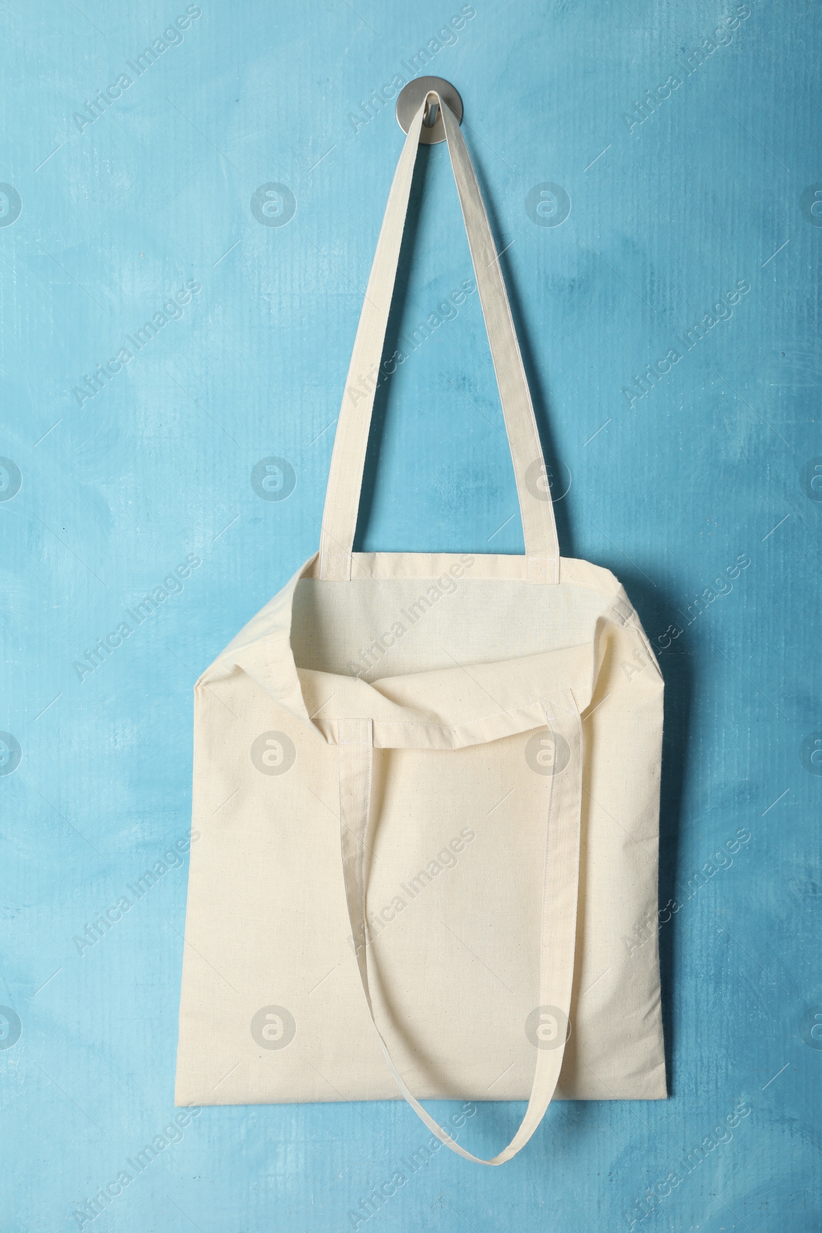 Photo of Eco bag hanging on light blue wall. Mockup for design