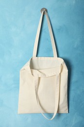 Photo of Eco bag hanging on light blue wall. Mockup for design