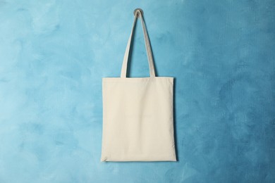 Photo of Eco bag hanging on light blue wall. Mockup for design