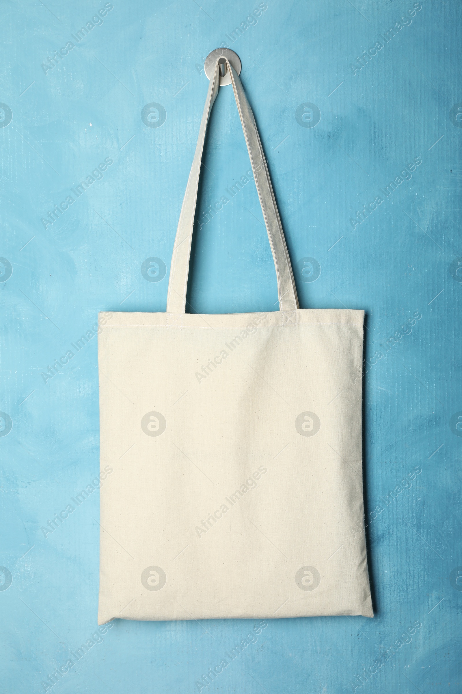 Photo of Eco bag hanging on light blue wall. Mockup for design