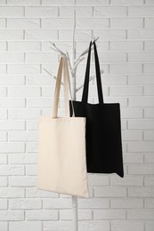 Photo of Eco bags hanging on clothing rack near white brick wall. Mockup for design