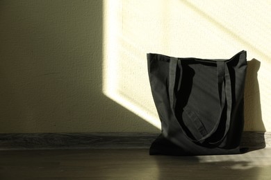 Black eco bag on floor near beige wall. Mockup for design