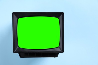 Image of Retro Tv set with green screen on light blue background, space for design. Chroma key