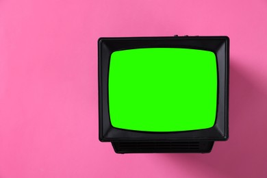 Image of Retro Tv set with green screen on pink background, space for design. Chroma key