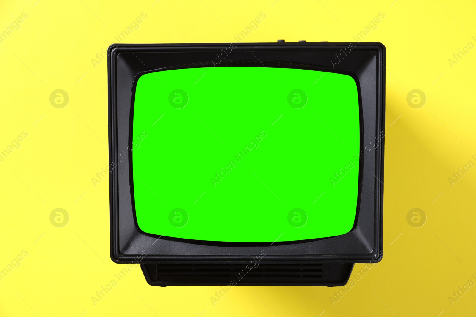 Image of Retro Tv set with green screen on yellow background. Chroma key