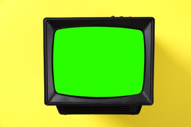 Image of Retro Tv set with green screen on yellow background. Chroma key