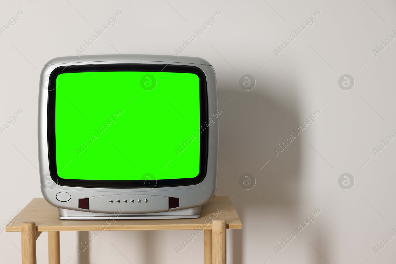 Image of Retro Tv set with green screen on wooden table near white wall, space for design. Chroma key