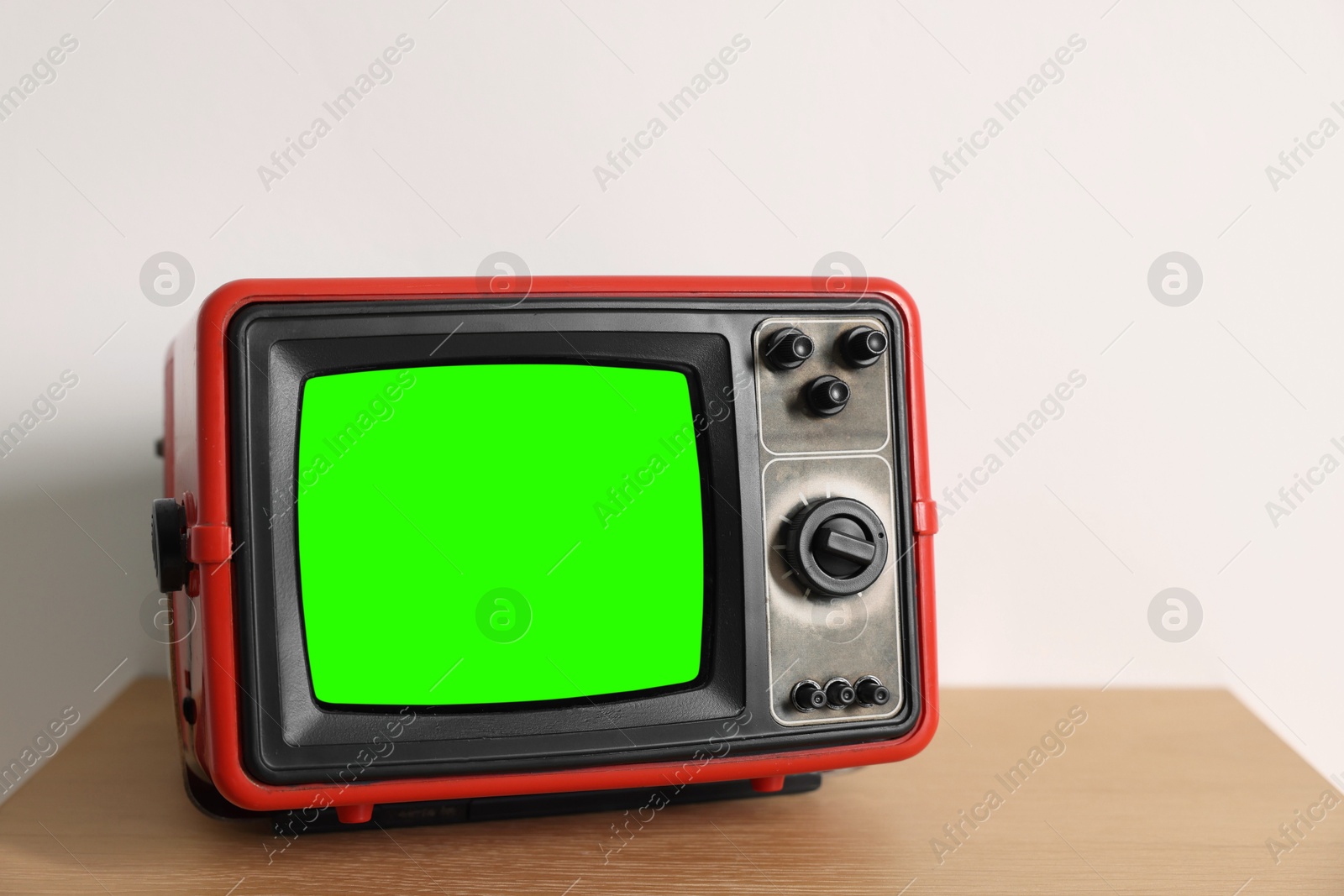 Image of Retro Tv set with green screen on wooden table near white wall, space for design. Chroma key