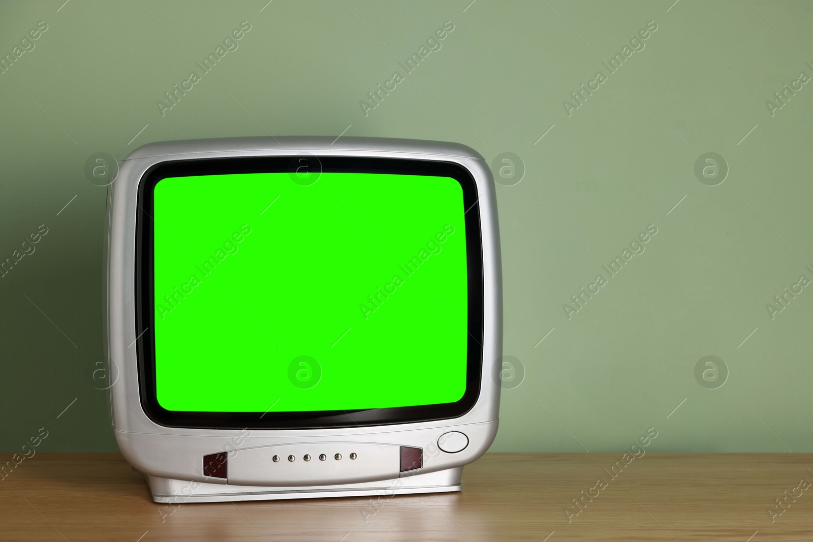 Image of Retro Tv set with green screen on wooden table near color wall, space for design. Chroma key