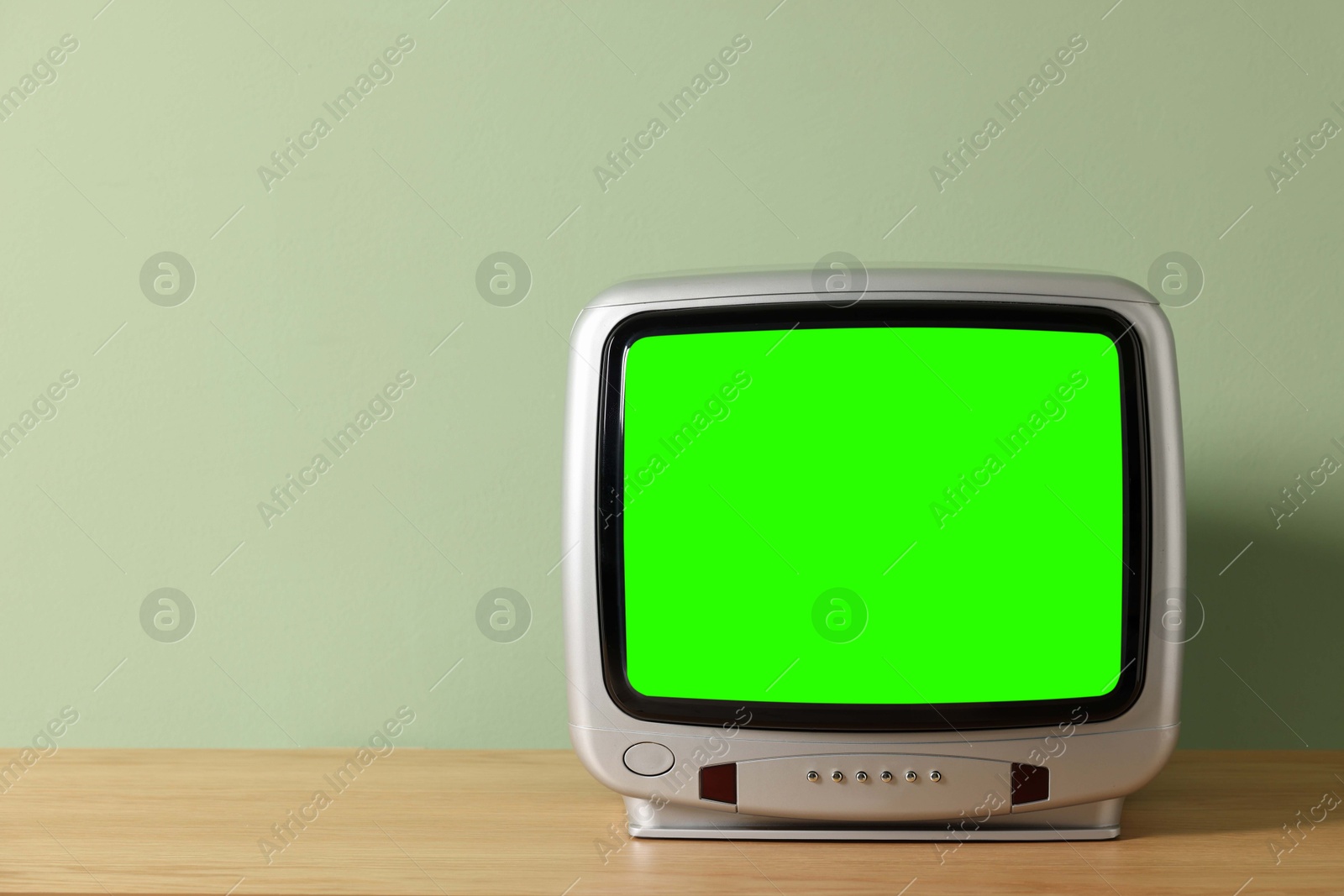 Image of Retro Tv set with green screen on wooden table near color wall, space for design. Chroma key