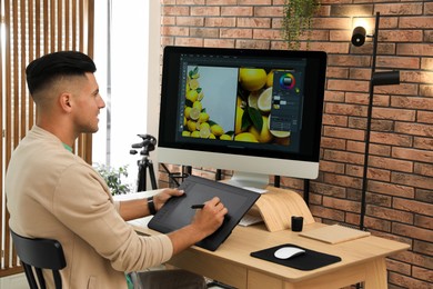 Photo of Professional retoucher working on graphic tablet at desk in office