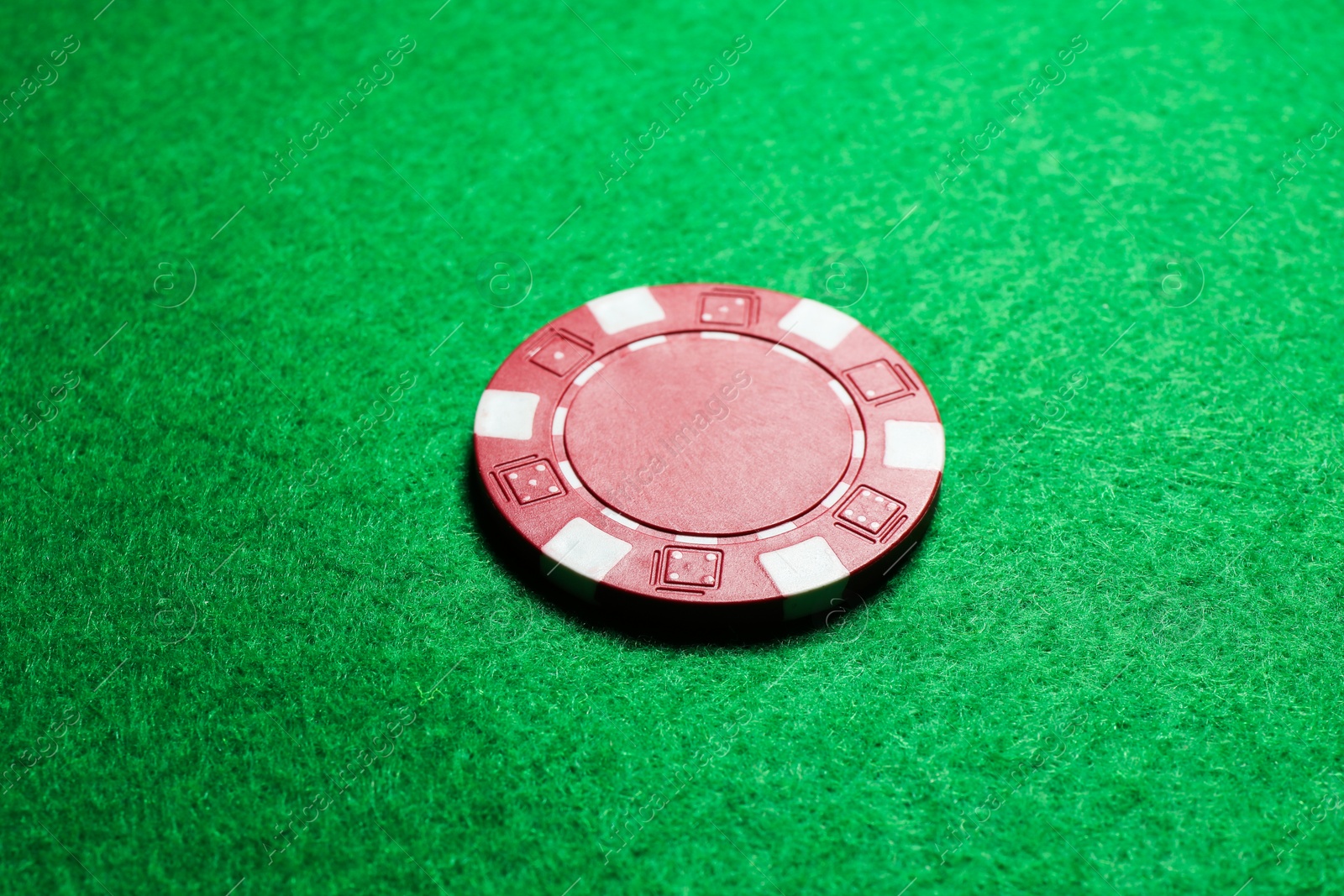 Photo of One poker chip on green table, closeup