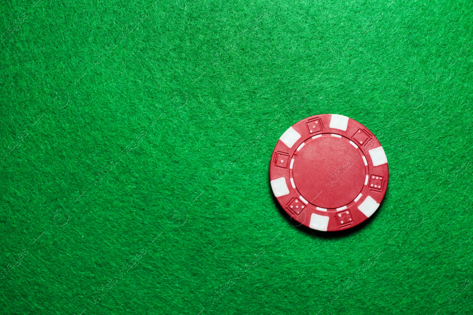 Photo of Poker chip on green table, top view. Space for text