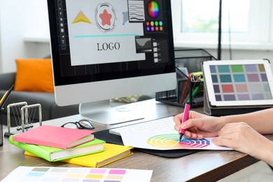 Photo of Designer working at wooden table indoors, closeup