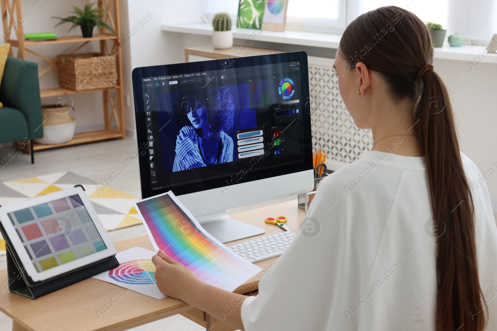 Photo of Designer with color palette working at wooden table indoors