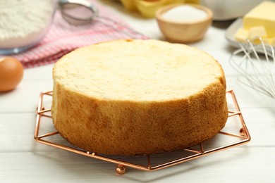 Tasty cut sponge cake on white wooden table