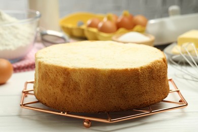 Tasty cut sponge cake on white wooden table, closeup