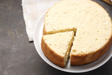 Tasty cut sponge cake on grey table