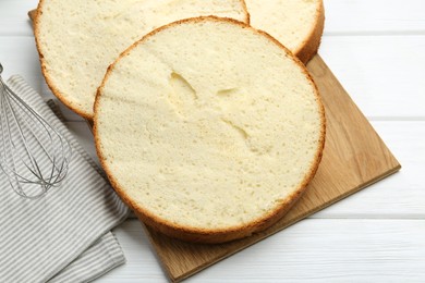 Photo of Delicious cut sponge cake on white wooden table