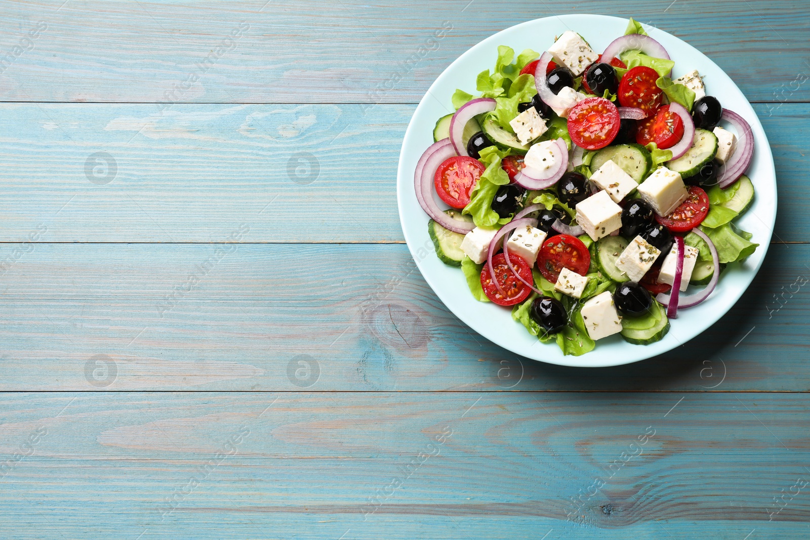 Photo of Delicious salad with feta cheese on blue wooden table, top view. Space for text